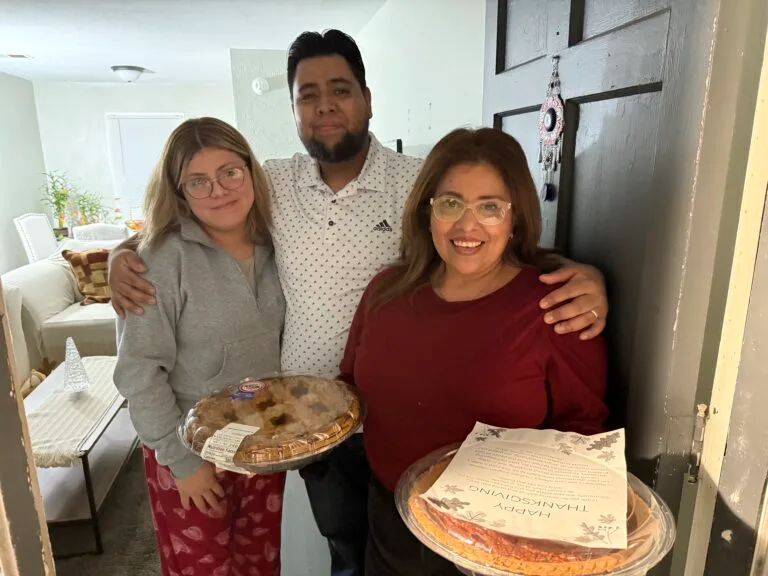 A happy family picture receiving thanksgiving pie in their hands.
